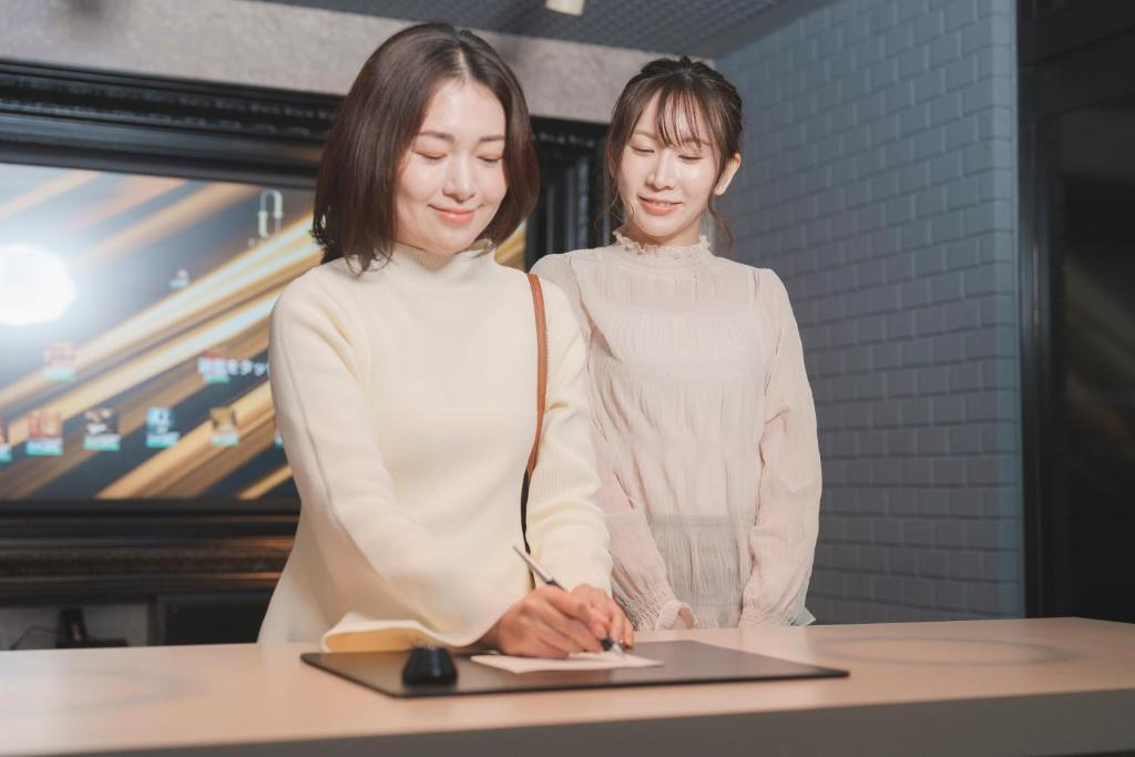 Deux femmes debout à une table avec un ordinateur portable dans l'établissement Asahikawa Hotel UNION-Adult Only, à Asahikawa