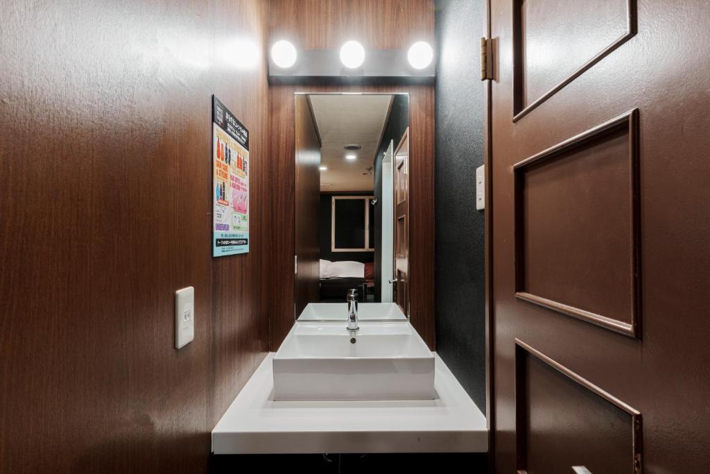 une salle de bain avec un lavabo blanc et un miroir dans l'établissement Asahikawa Hotel 818-Adult Only, à Asahikawa