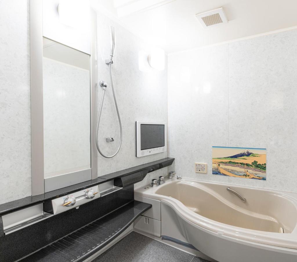 une salle de bain avec une baignoire et une télévision au mur dans l'établissement Asahikawa Hotel COLOR'S-Adult Only, à Asahikawa
