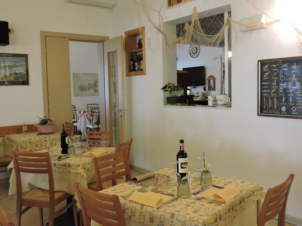 - une salle à manger avec 2 tables et des bouteilles de vin dans l'établissement Hotel Il Pino, à San Vincenzo