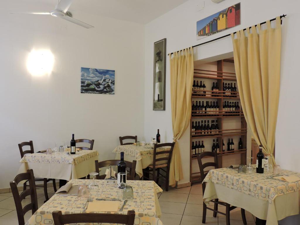 - un restaurant avec des tables, des chaises et des bouteilles de vin dans l'établissement Hotel Il Pino, à San Vincenzo