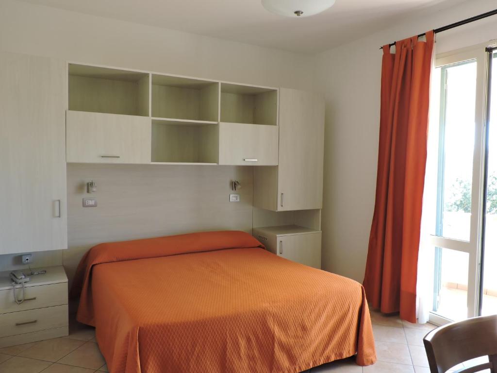 une chambre avec un lit avec une couverture orange dans l'établissement Hotel Il Pino, à San Vincenzo