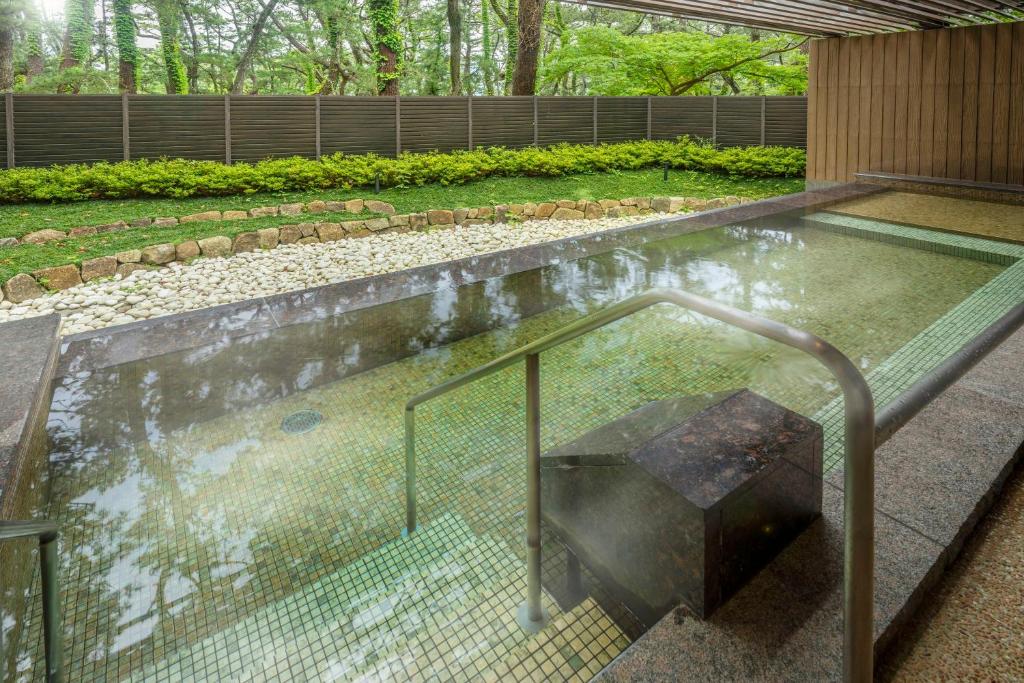 un jacuzzi dans un jardin avec une balustrade en métal dans l'établissement KAMENOI HOTEL Kamogawa, à Kamogawa