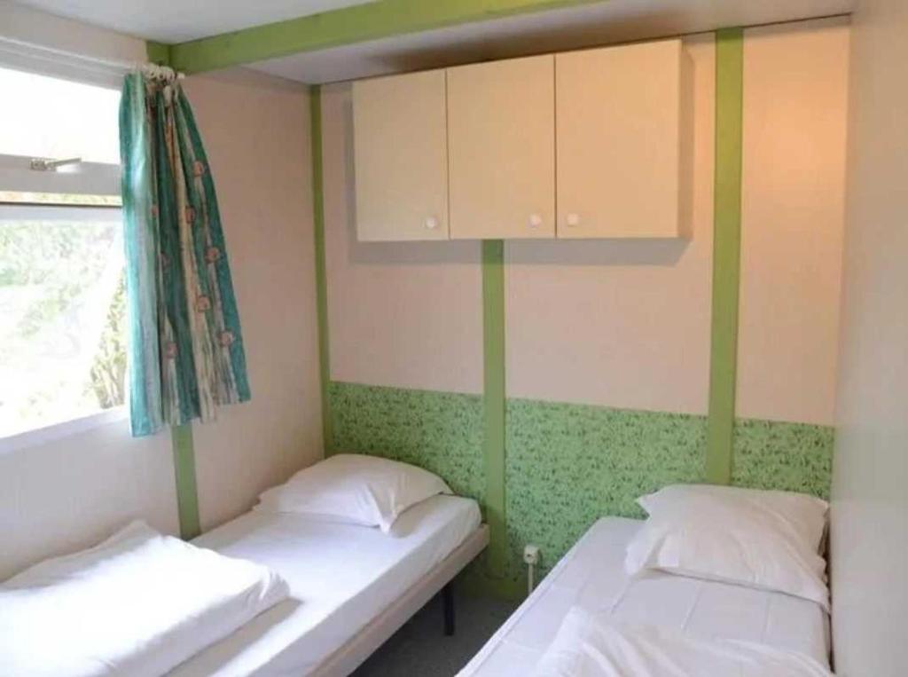 - 2 lits dans une chambre de couleur verte et blanche dans l'établissement Camping 3 étoiles - Piscine - cbgcaia, à Buis-les-Baronnies