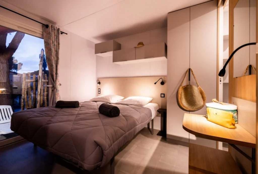 une chambre avec un grand lit et une fenêtre dans l'établissement Camping 4 étoiles - Parc aquatique - ccaffga, au Cap d'Agde