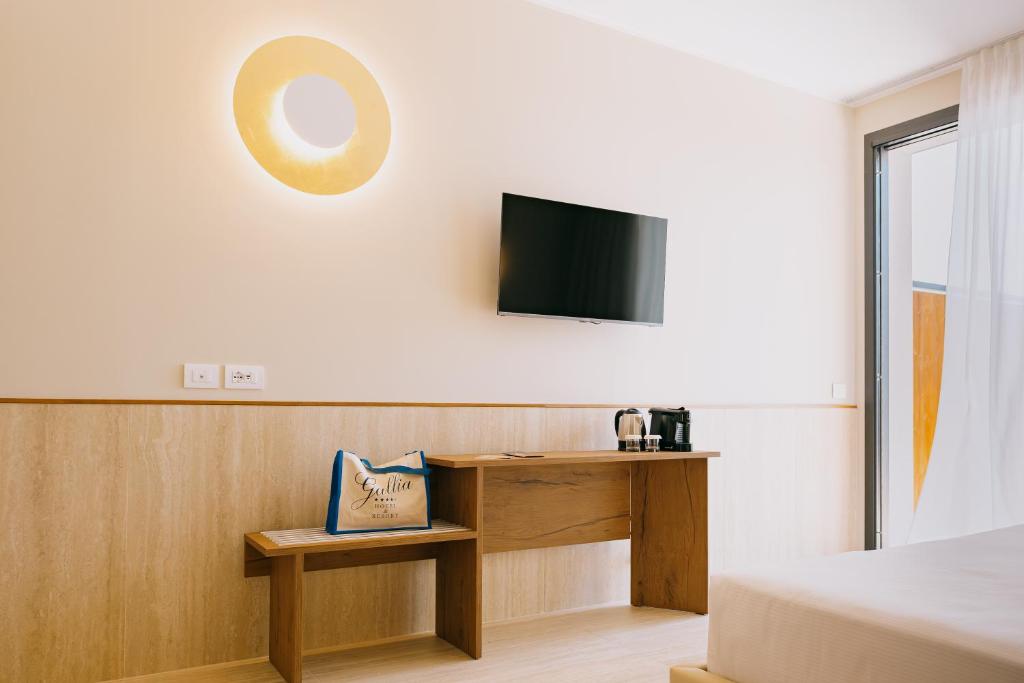 une chambre avec un bureau et une télévision au mur dans l'établissement Hotel Gallia & Resort, à Lido di Jesolo