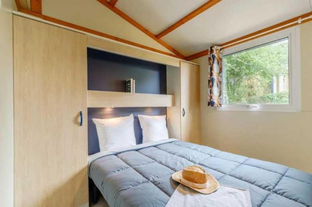 - une chambre avec un lit et un chapeau sur une table dans l'établissement Camping 3 étoiles - Piscine - ccafbhe, à Saint-Hilaire-de-Talmont 37 autres photos