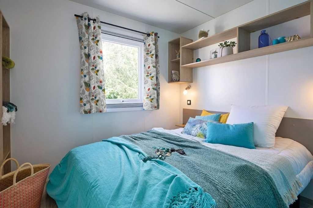 une chambre avec un lit bleu avec une fenêtre dans l'établissement Camping 3 étoiles - Piscine - eecbb0, à Guérande