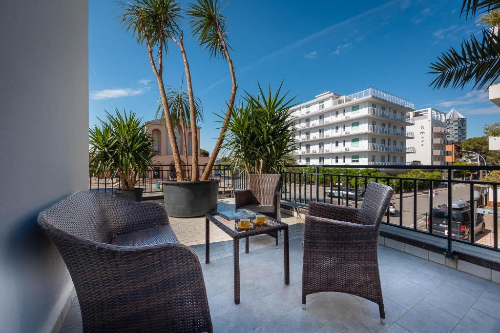 d'un balcon avec des chaises, une table et des palmiers. dans l'établissement Hotel Portofino, à Lido di Jesolo