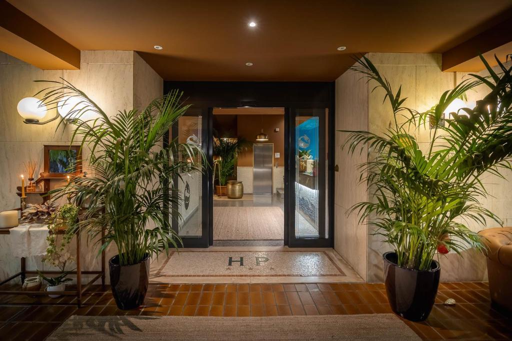 un hall avec deux plantes en pot devant une porte dans l'établissement Hotel Portofino, à Lido di Jesolo