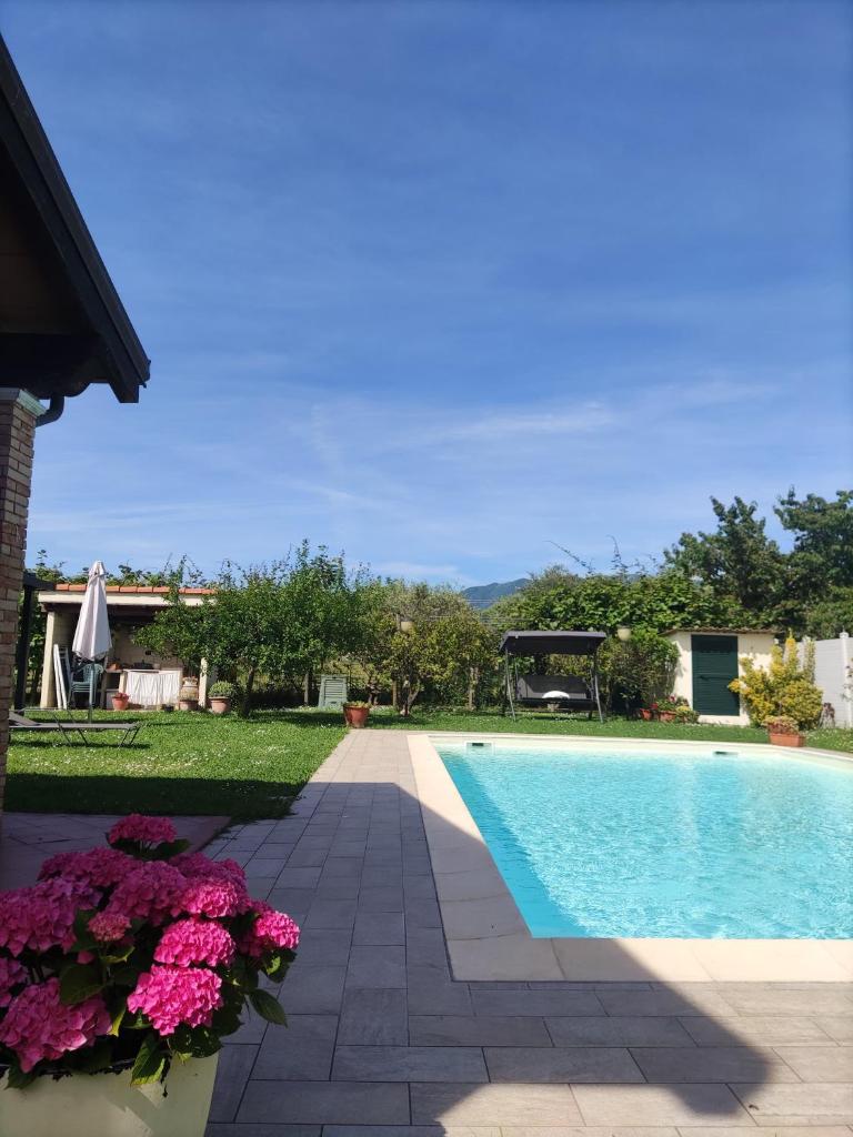 une piscine avec des fleurs à côté d'une maison dans l'établissement Ca'Melia Villetta, à Sarzana