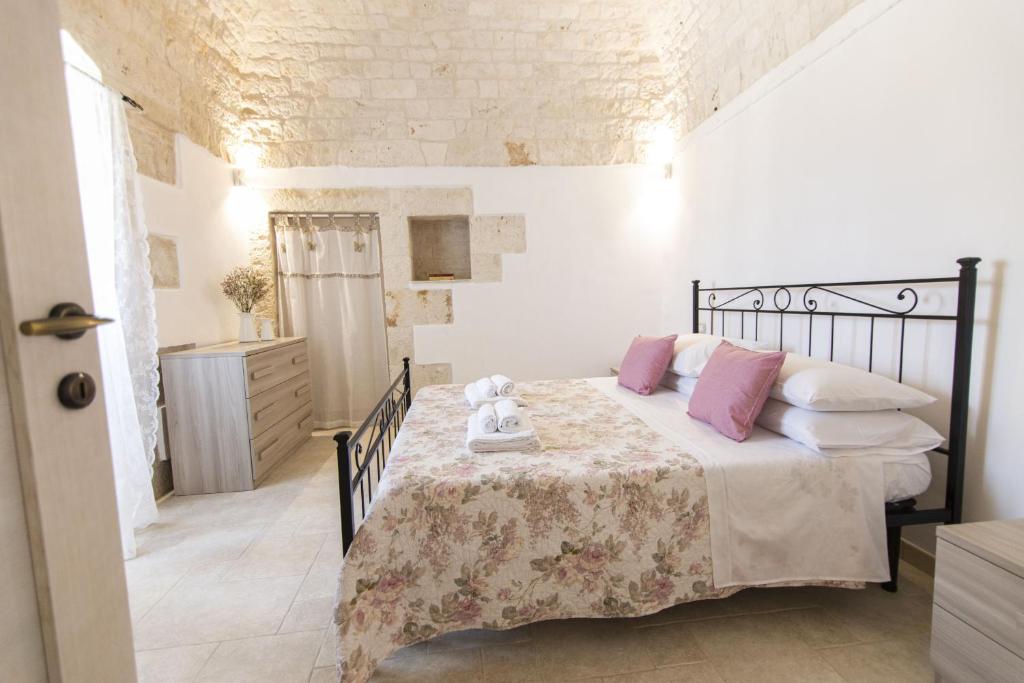 une chambre avec un lit avec des oreillers roses et blancs dans l'établissement La catena, à Martina Franca