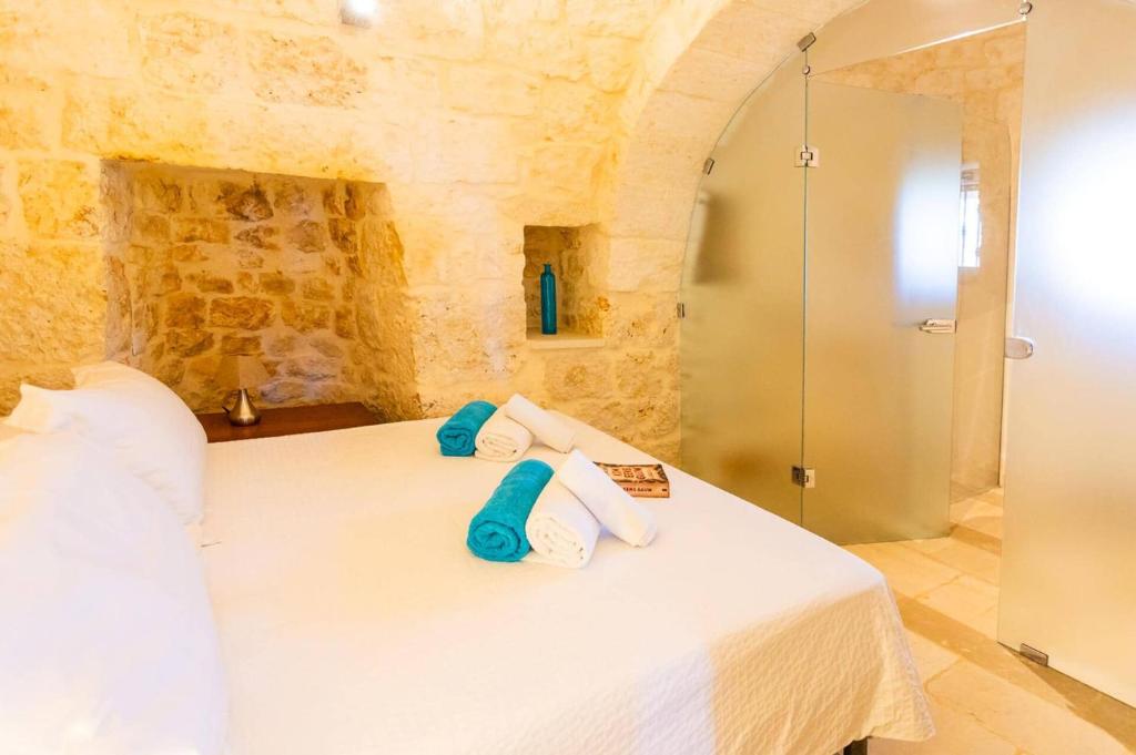 une chambre avec un lit blanc avec des oreillers bleus dans l'établissement Villa Trullo Selva Grande by Villa Plus, à Martina Franca