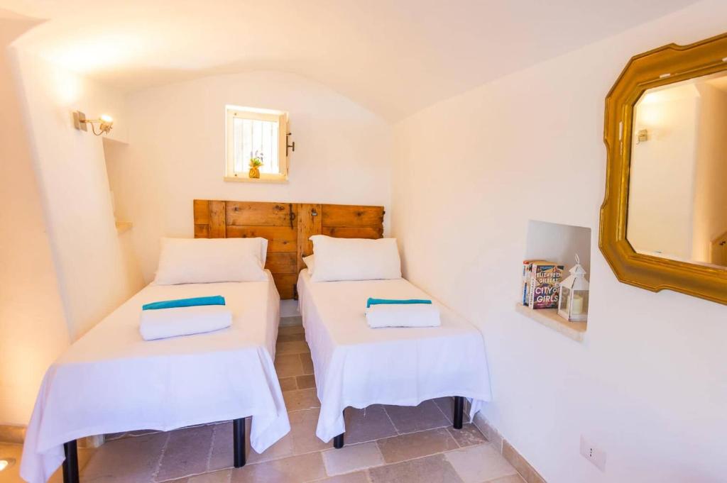 deux lits dans une petite pièce avec un miroir dans l'établissement Villa Trullo Selva Grande by Villa Plus, à Martina Franca