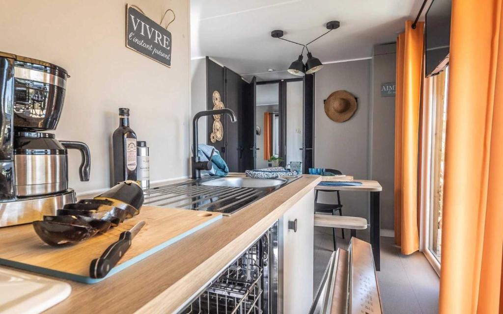une cuisine avec un évier et une cuisinière four supérieur dans l'établissement Camping 4 étoiles - Parc aquatique - eeic0a, à La Tranche-sur-Mer