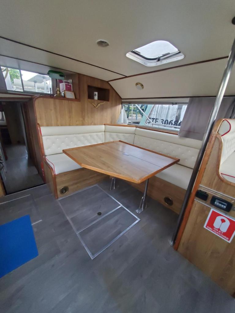 un salon avec une table à l'arrière d'une camionnette dans l'établissement BATEAU - Jolie pénichette sur région touristique., à Bellegarde