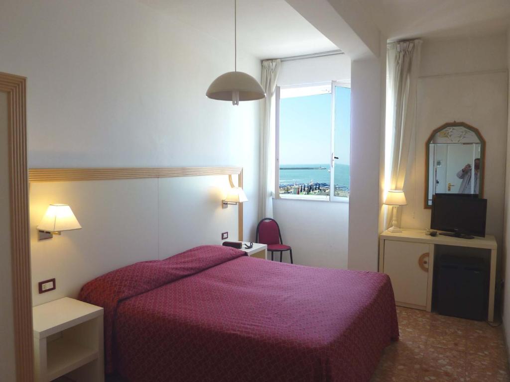 une chambre d'hôtel avec un lit violet et une fenêtre dans l'établissement Hotel Liberty, à Viareggio