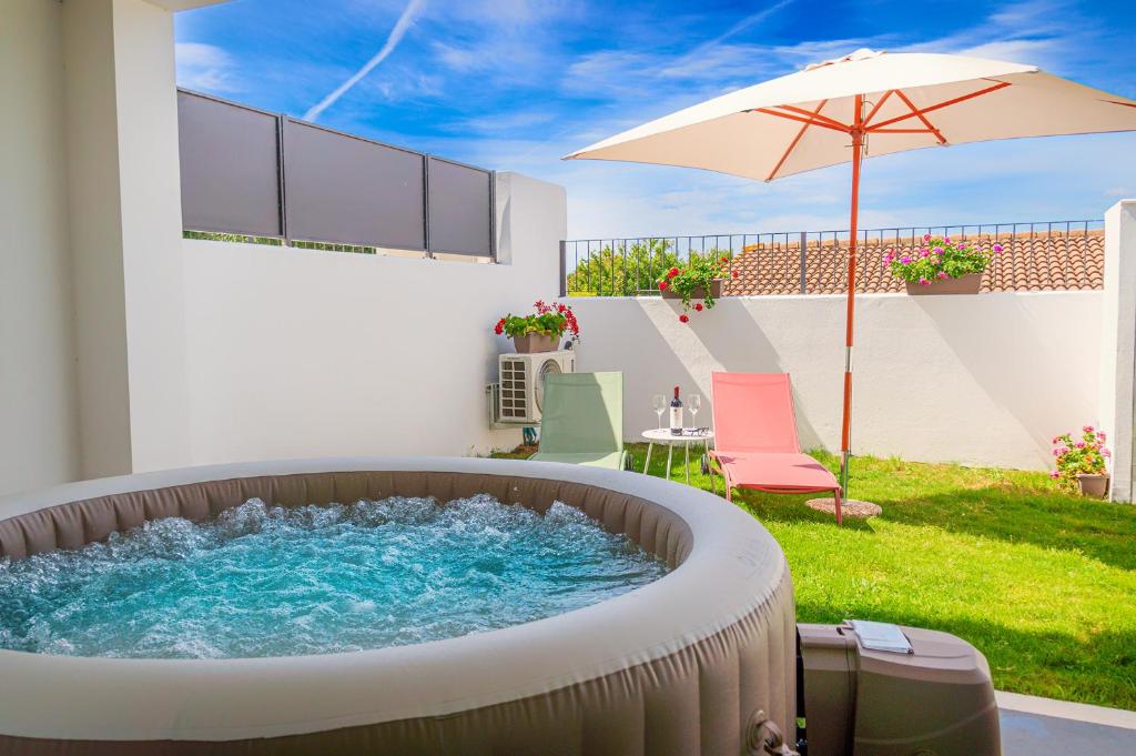 - un bain à remous dans une cour avec un parasol dans l'établissement Villa Manzoni, à Àrbatax