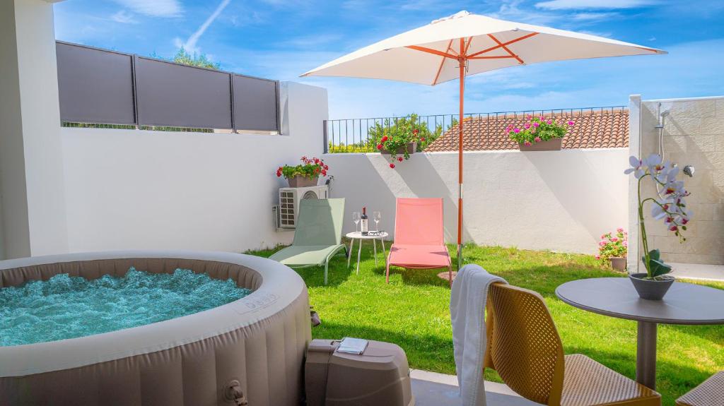 une cour avec un bain à remous et un parasol dans l'établissement Villa Manzoni, à Àrbatax