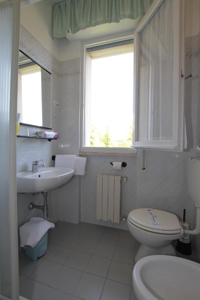 une salle de bain avec toilettes, lavabo et fenêtre dans l'établissement Hotel Vera, à Marina di Massa