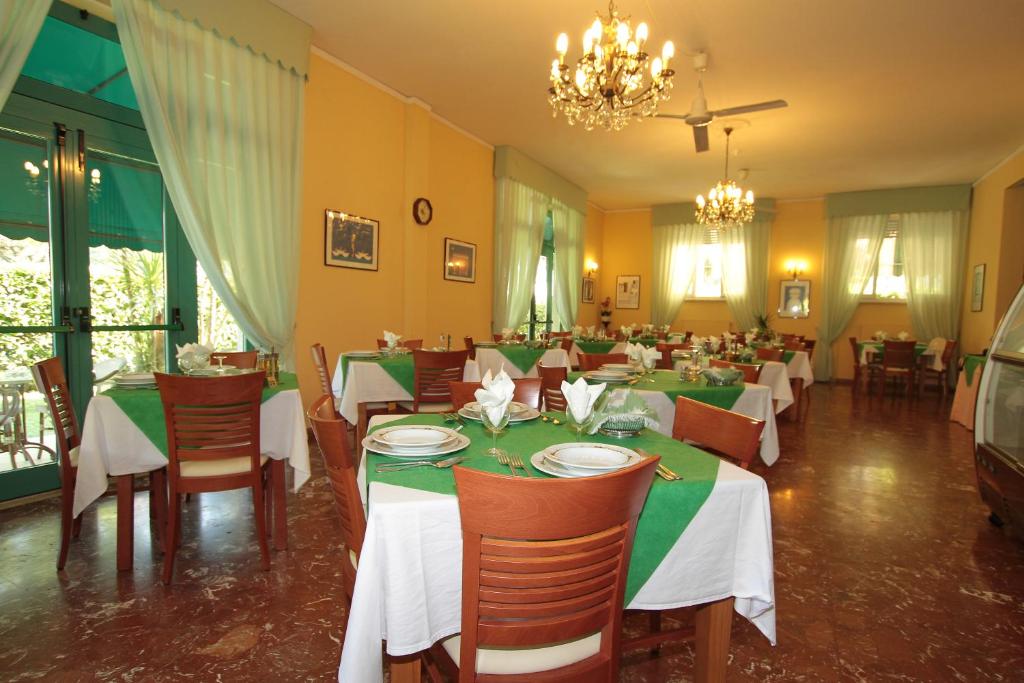 une salle à manger avec tables et chaises et un lustre dans l'établissement Hotel Vera, à Marina di Massa