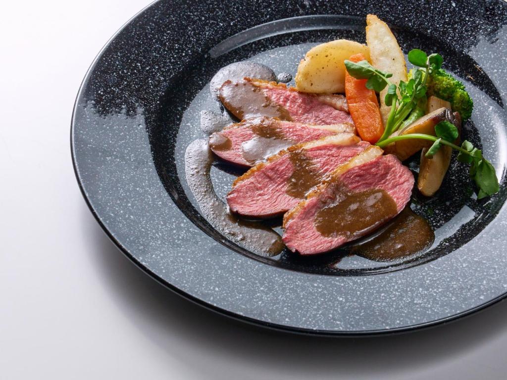 une plaque de nourriture contenant de la viande et des légumes dans l'établissement Ishinoyu Lodge, à Yamanouchi