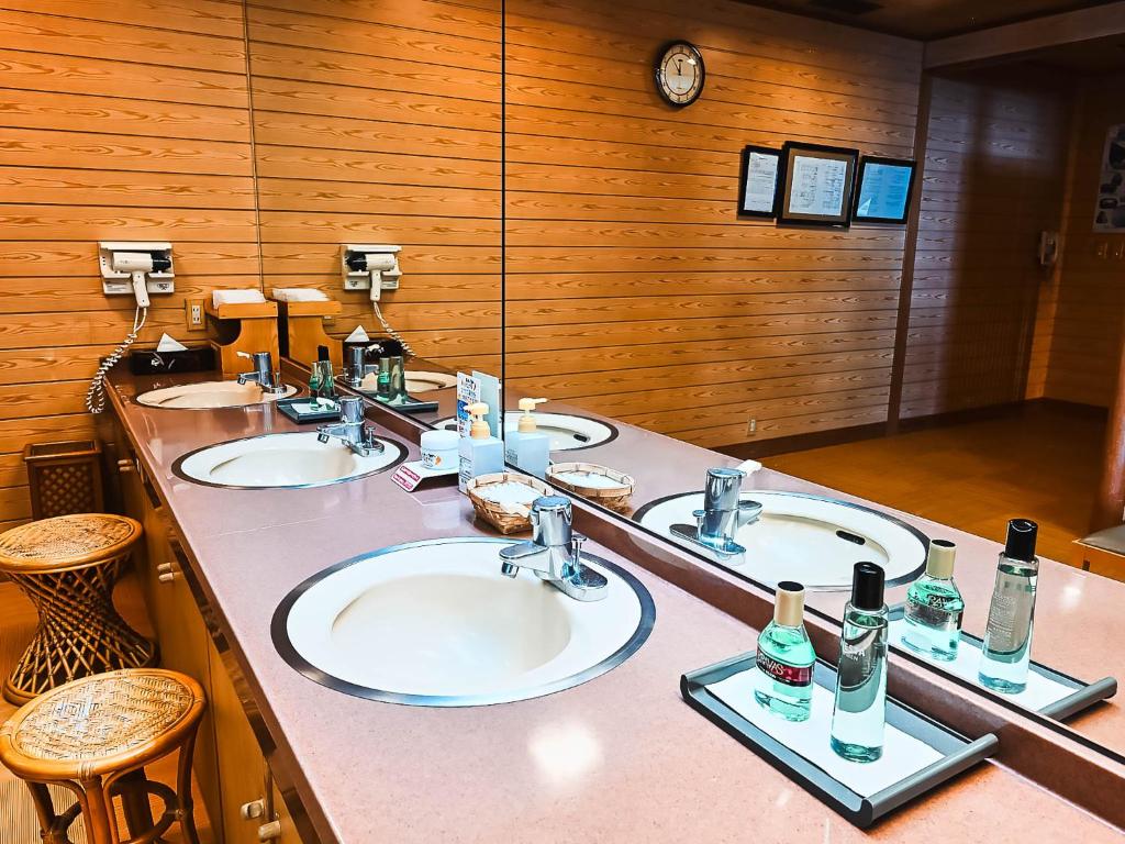 une salle de bain avec trois lavabos et deux miroirs dans l'établissement Shin Kadoya, à Atami
