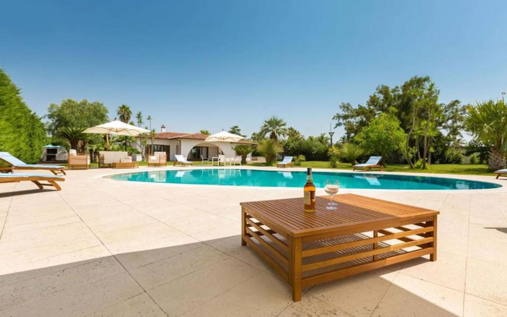- une bouteille de vin assise sur une table près de la piscine dans l'établissement Villa Carrisi - Salento Reservation, à Parabita