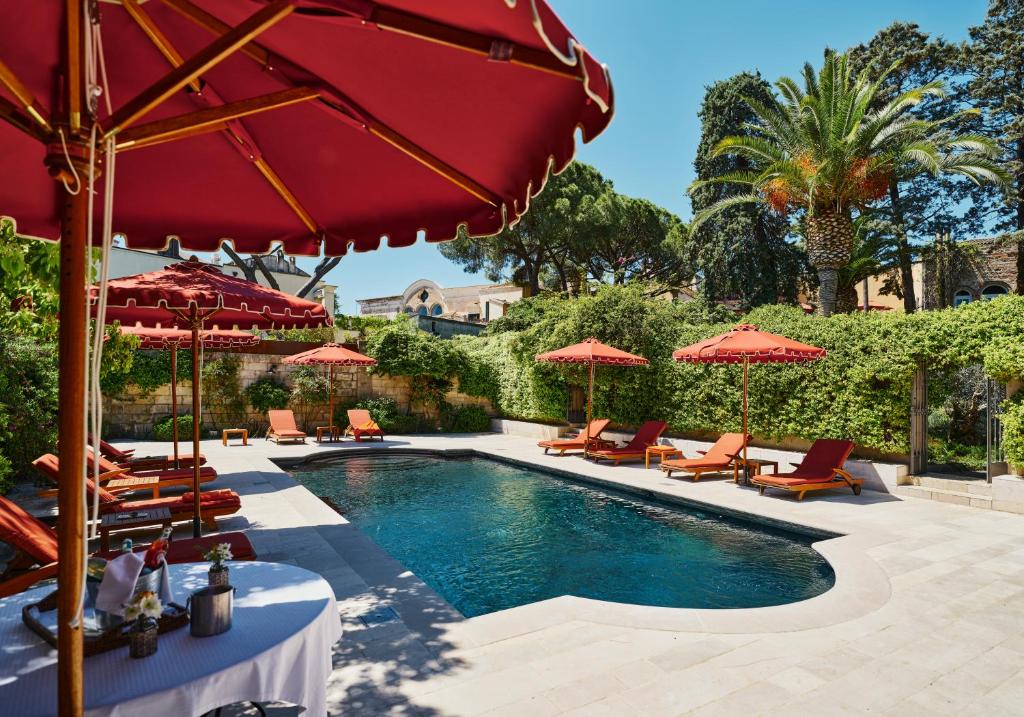 une piscine avec des parasols rouges et des chaises longues et une piscine dans l'établissement Palazzo Margherita, à Bernalda