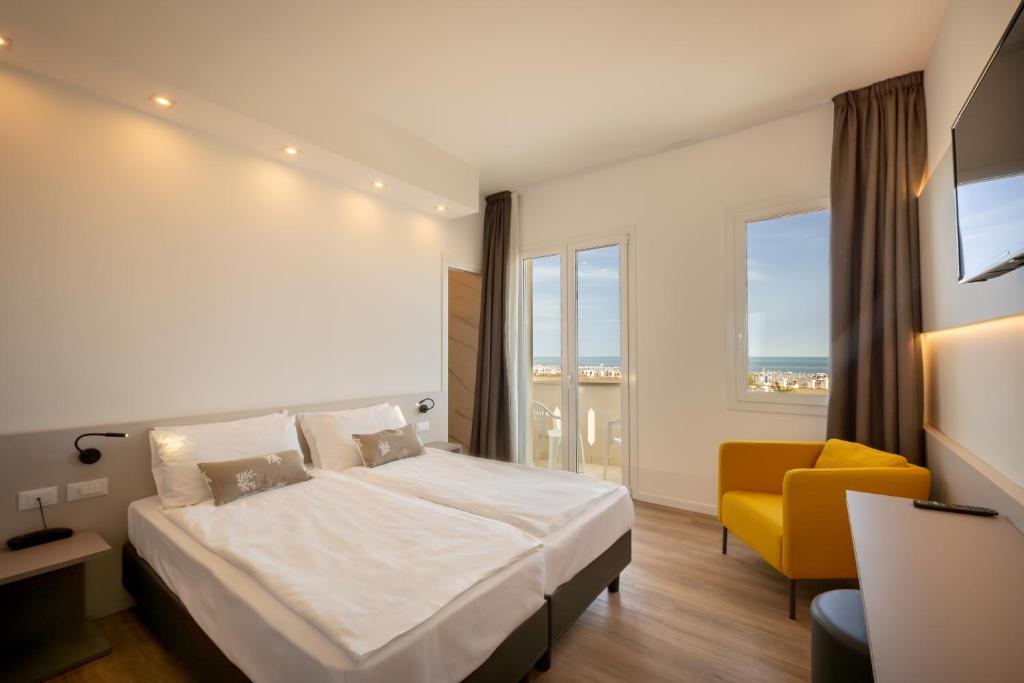 une chambre d'hôtel avec un lit et une chaise jaune dans l'établissement Hotel Delfino, à Caorle