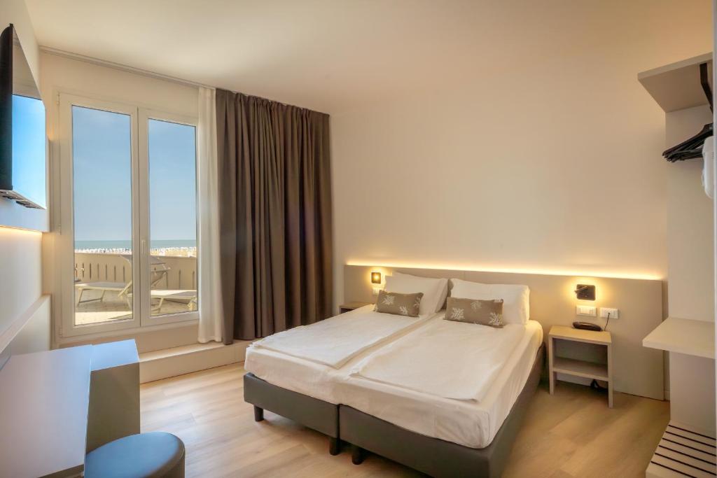 une chambre d'hôtel avec un lit et une grande fenêtre dans l'établissement Hotel Delfino, à Caorle
