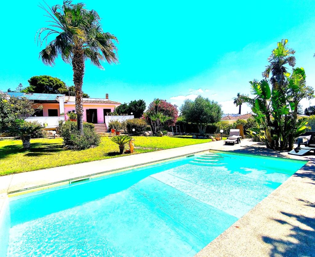 une piscine devant une maison avec des palmiers dans l'établissement Nettuno 2023, à Marina di Ragusa