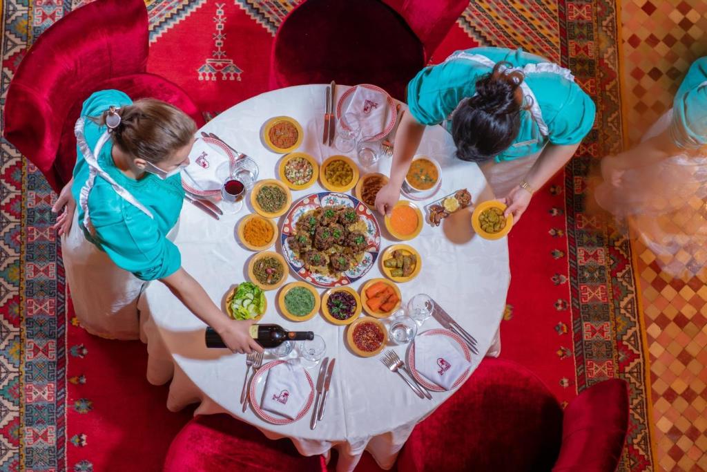 deux femmes debout à une table avec une assiette de nourriture dans l'établissement Al Fassia Aguedal, à Marrakech
