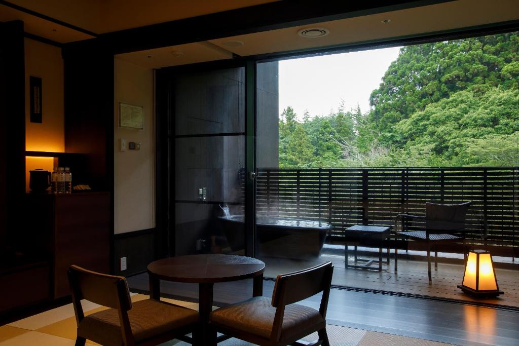 - un salon avec une table, des chaises et une grande fenêtre dans l'établissement Hakone Kowakien Tenyu, à Hakone