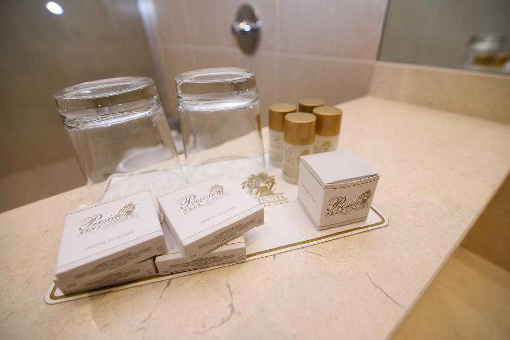 - un comptoir de salle de bains avec deux bocaux et des boîtes en verre dans l'établissement Grand Hotel President, à Siderno Marina