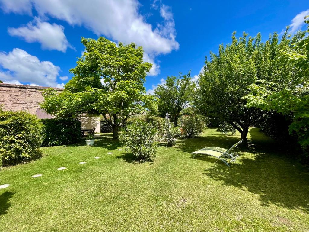 un jardin avec des arbres et un banc dans la pelouse dans l'établissement La belle histoire Gîte Ventoux, à Bédoin