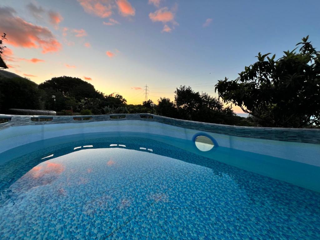 une piscine avec un coucher de soleil en arrière-plan dans l'établissement Villa La Terrazza Sul Mare di Trabia, à Trabia