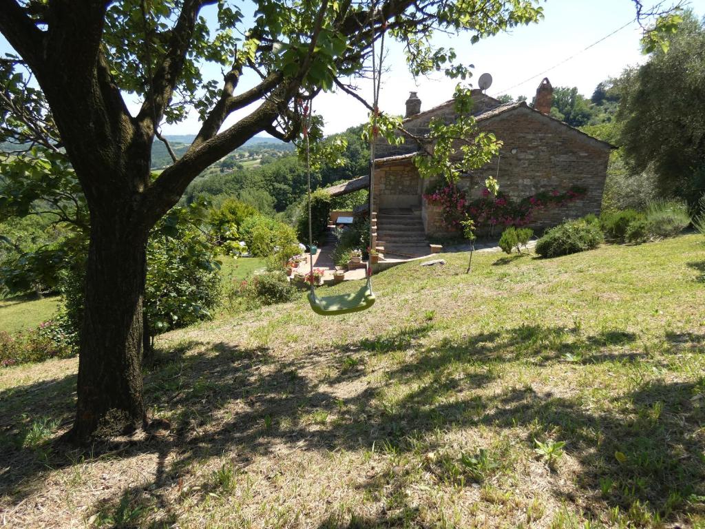 une balançoire suspendue à un arbre devant une maison dans l'établissement SCAPPO IN UMBRIA, il Fienile, à Fornole