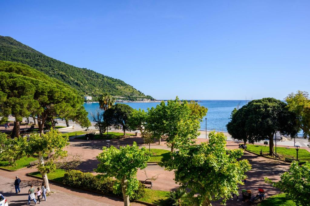 un parc avec des arbres et l'océan en arrière-plan dans l'établissement Hotel Tirreno, à Sapri