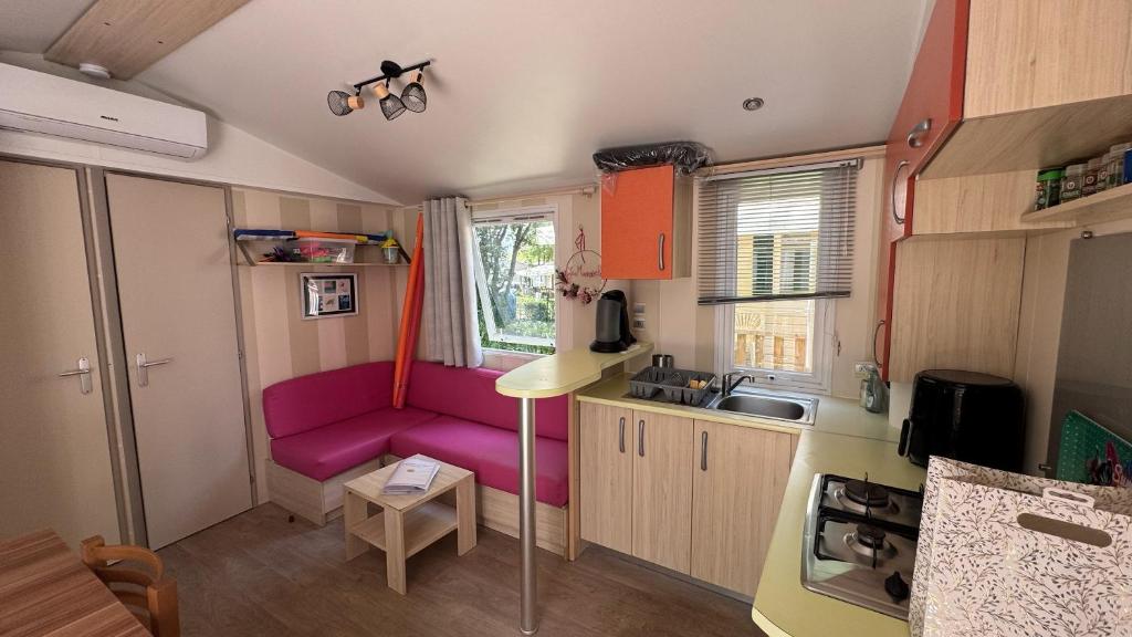 une petite cuisine avec un canapé rose dans une caravane dans l'établissement Mobil-home Le Manosely confort 6 pers Climatisé, à Agde
