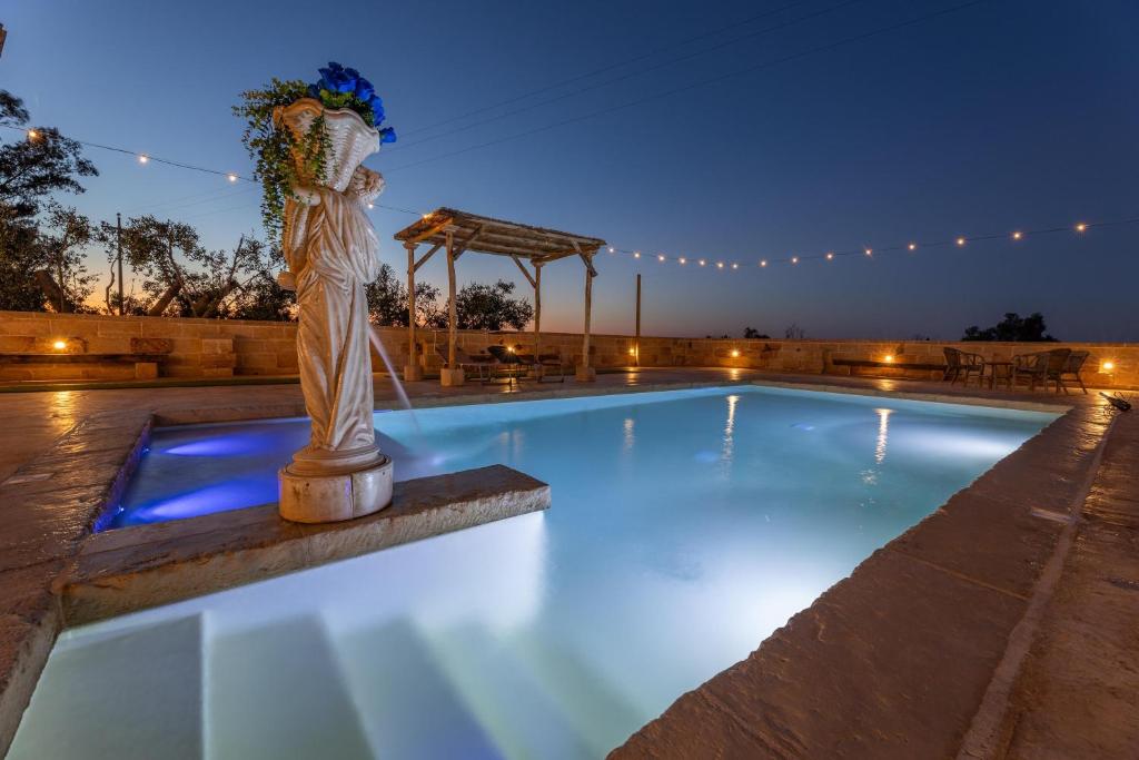 - une piscine de nuit avec une statue au milieu dans l'établissement Villa Galatea, à Galatone
