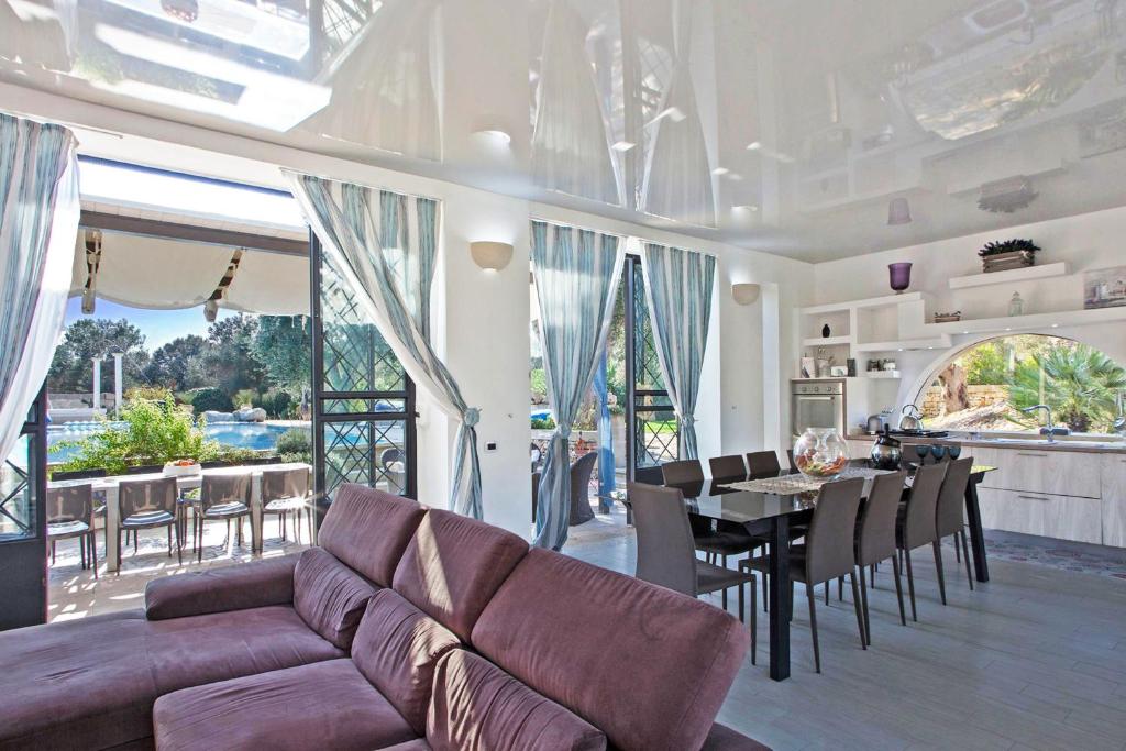 un salon avec un canapé et une table avec des chaises dans l'établissement Tenuta Bouganville With Garden And Pool - Happy Rentals, à Carpignano Salentino