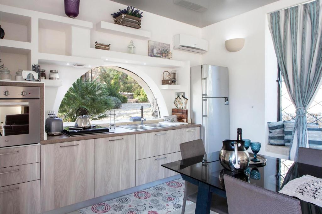 La cuisine est équipée d'un évier, d'un réfrigérateur et d'une table. dans l'établissement Tenuta Bouganville With Garden And Pool - Happy Rentals, à Carpignano Salentino