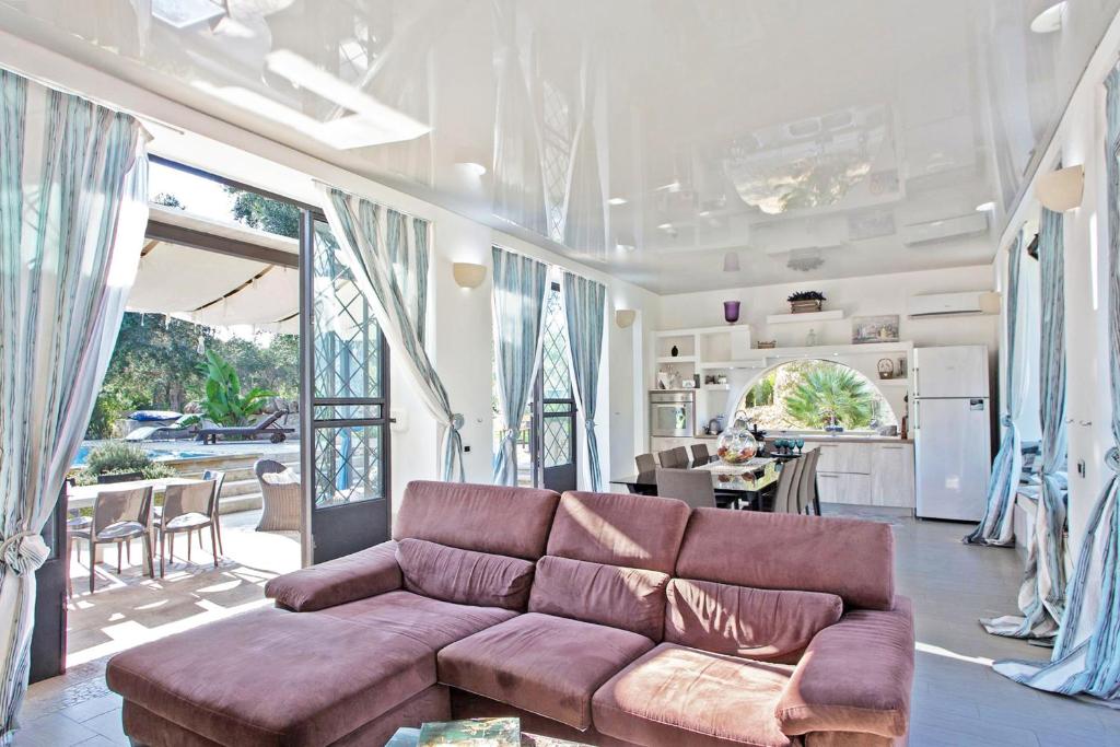 un salon avec un canapé marron et une cuisine dans l'établissement Tenuta Bouganville With Garden And Pool - Happy Rentals, à Carpignano Salentino