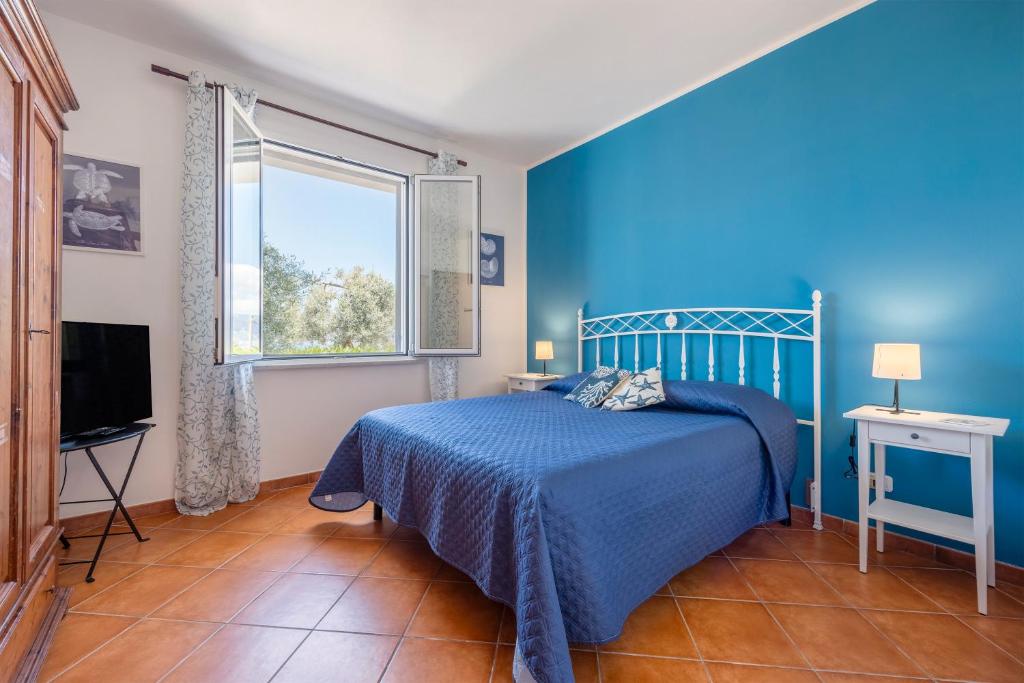 une chambre bleue avec un lit et une fenêtre dans l'établissement Villa Anna Messina, à Carini