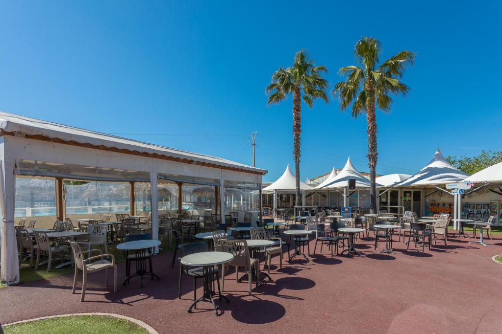 un patio avec tables, chaises et palmiers dans l'établissement Le Mediterranéen, à Fréjus