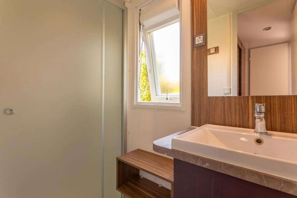 une salle de bain avec un lavabo et un miroir dans l'établissement Le Mediterranéen, à Fréjus