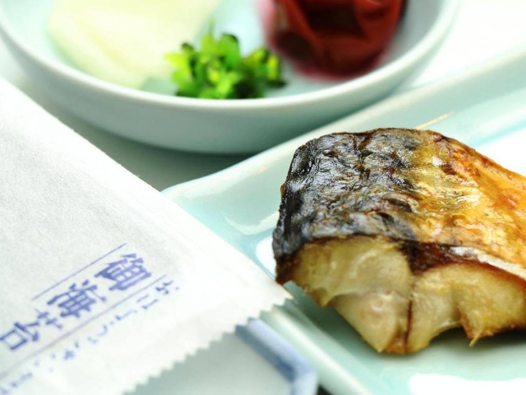 un plat sur une assiette avec un bol de salade dans l'établissement Ryokan Kamomeso, à Sado