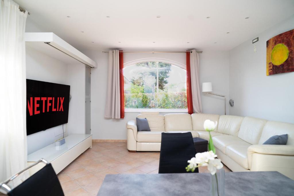 un salon avec un canapé blanc et une télévision dans l'établissement Moderna villa con piscina a due Passi dal Golf Club, à Pavona