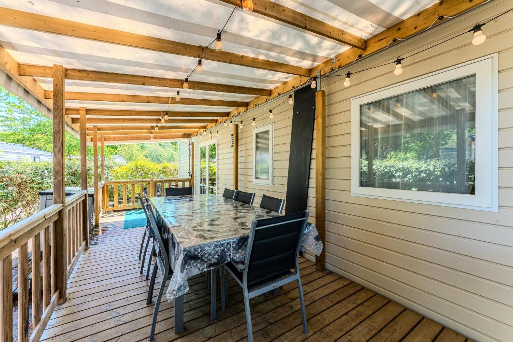 un patio avec une table et des chaises sur une terrasse dans l'établissement Mobil-home camping Gastes Landes, à Gastes